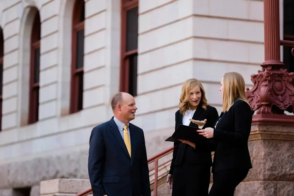 Personal injury attorney Ryan Malnar and legal team discussing a case on the steps of a Colorado courthouse.