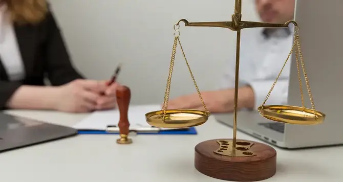 Gold scales of justice on a law firm desk during an attorney-client consultation, representing legal equality and expert personal injury representation.