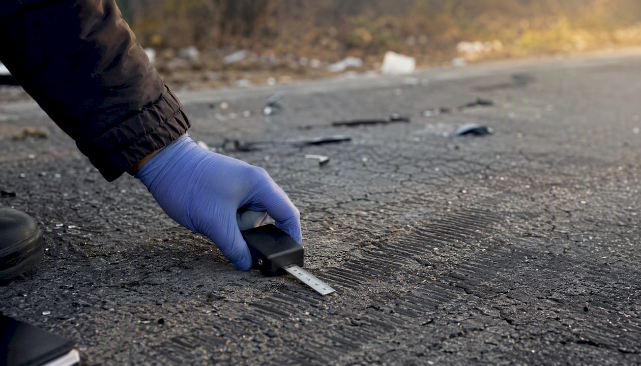 Hand measuring tire marks at accident scene