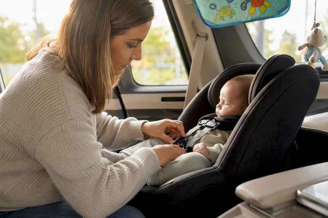 Hands adjusting harness on rear-facing car seat