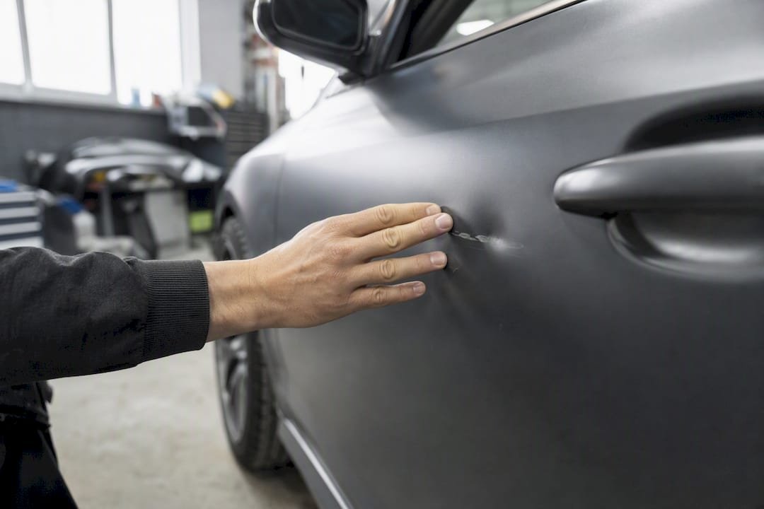 Close-up of hand inspecting car collision damage