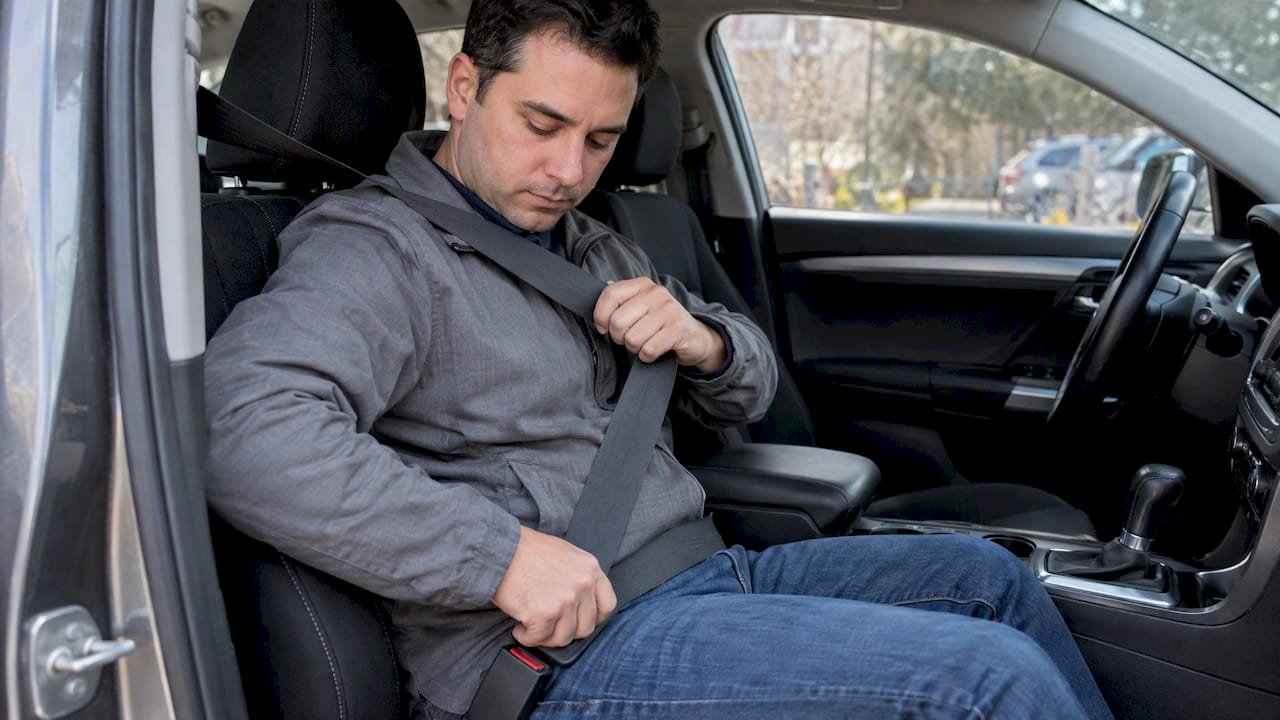 Passenger fastening a correctly positioned seat belt